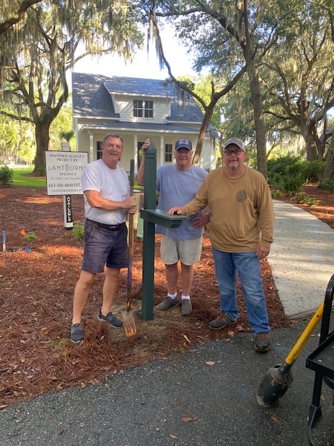 Three CPV volunteers installing a mailbox post outside a neighborhood home