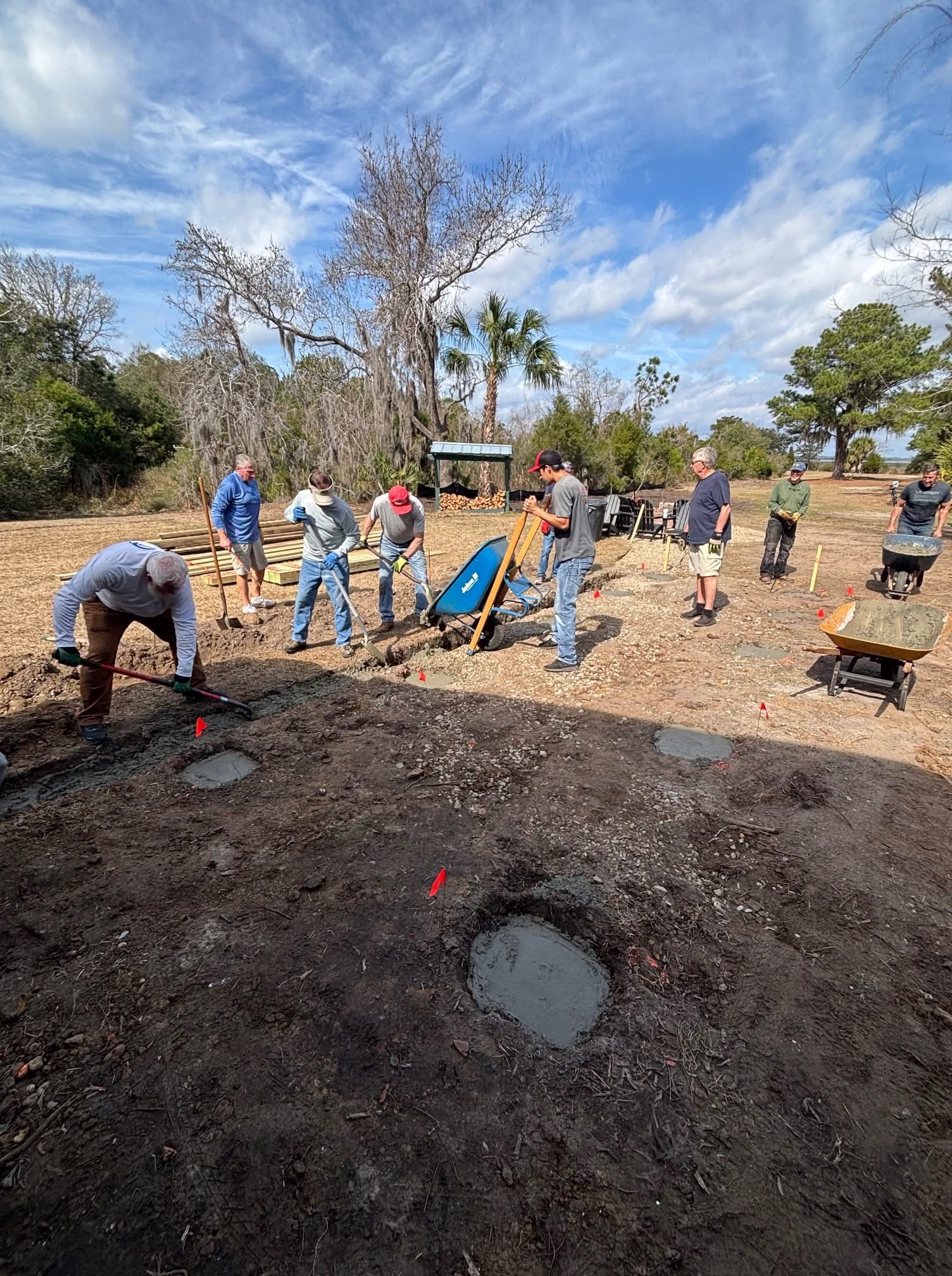Large group of CPV volunteers digging and grading with wheelbarrows at a community work site