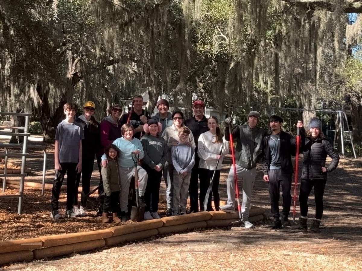 Large group of CPV volunteers and families posing at the playground renovation site